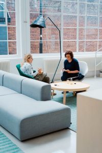 two people sitting and conversing in an open bright space